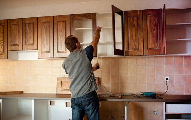 man installing cabinets in kitchen