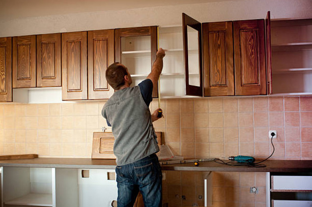man installing cabinets in kitchen